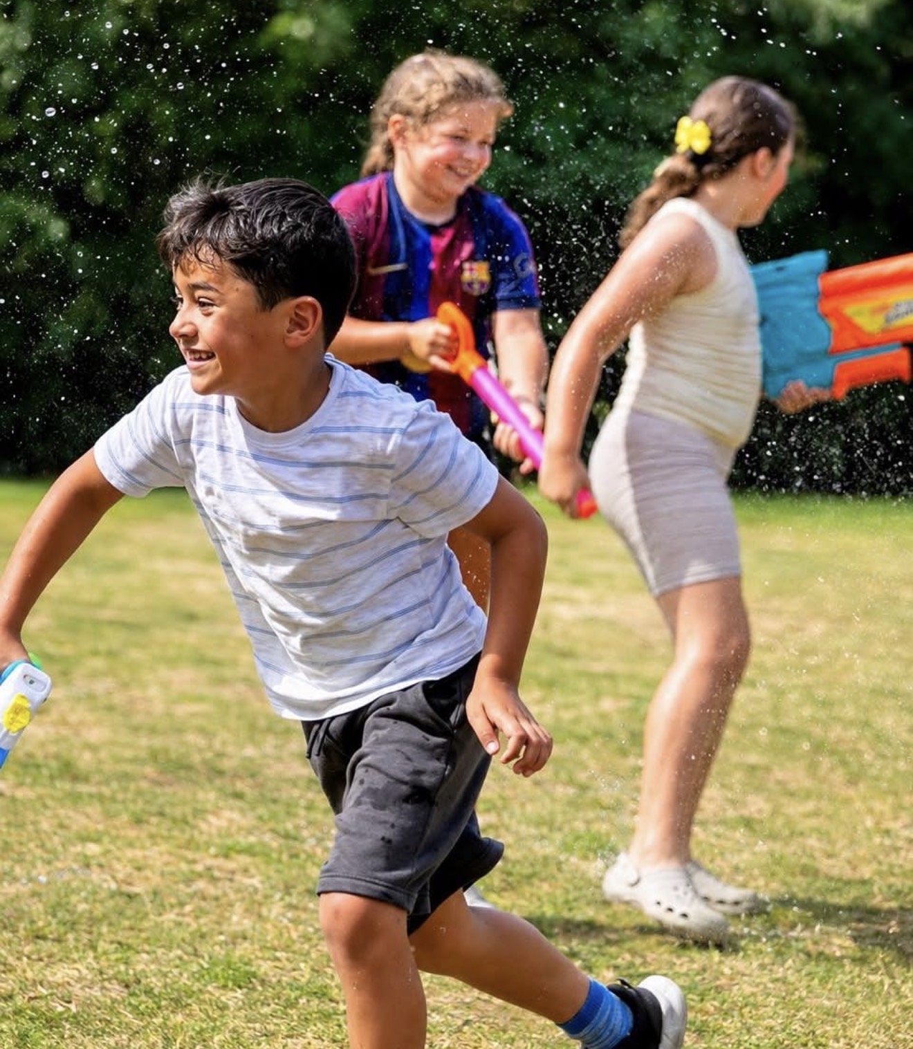 Children laughing during a water fight at an Inspire holiday camp